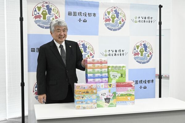 ふるさと納税返礼品のボックスティッシュを前に笑顔を見せる浅野市長