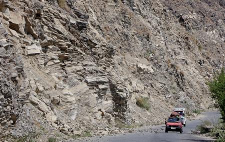 アフガニスタン東部クナール州ヌールガルで、落石を避けて通る車=5日(共同)