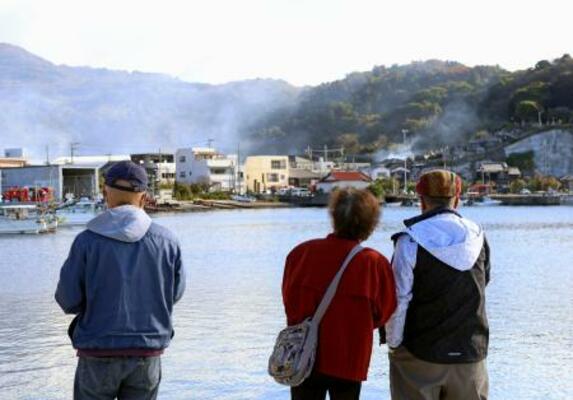 大分市佐賀関の大規模火災現場を見つめる人たち=19日午前9時41分