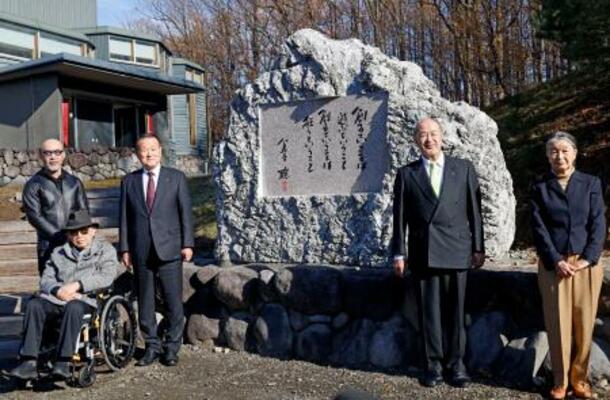 「富良野演劇工場」に寄贈した石碑の前で記念撮影する倉本聰さん(左端手前)=16日午前、北海道富良野市