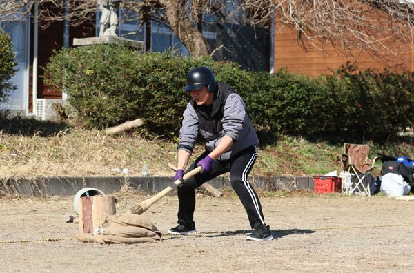 棍棒飛ばしを体験する記者。思った場所に殴打棒を振り下ろすのが難しい