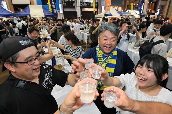 地酒を手に乾杯する来場者たち＝30日午後７時25分、宇都宮市江野町
