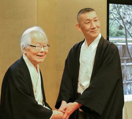 　下鴨神社の宮司交代が発表され、握手する前宮司の新木直人氏（左）と新宮司の友田重臣氏＝３日午後、京都市左京区