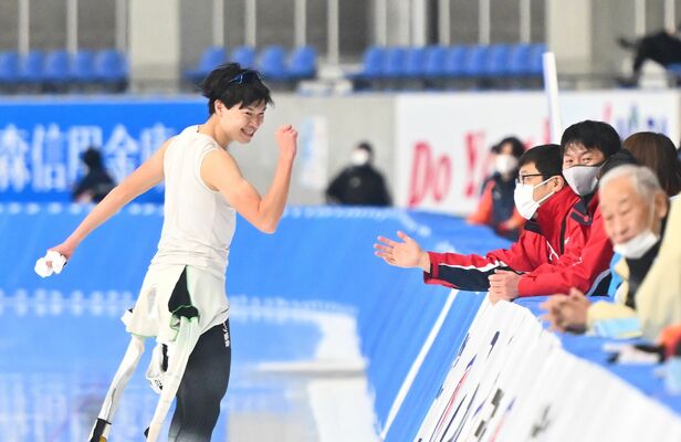 スピード成年男子５０００メートル決勝を３位で終え、コーチ陣のねぎらいにガッツポーズで応える本県の小川＝ＹＳアリーナ八戸