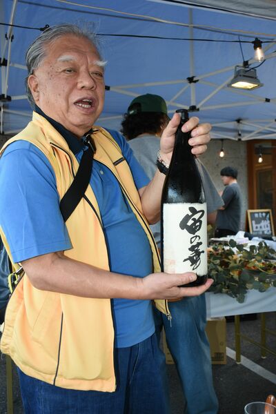 古酒を手にし、各テーブルに注いで回る参加者＝６月６日、宇都宮市