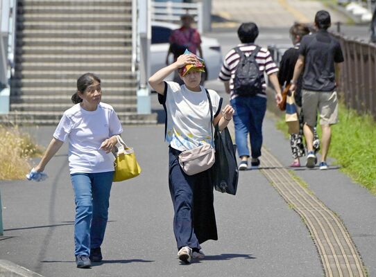 タオルで強い日差しを避けるなどして歩く人たち＝７日午後０時40分、佐野市越名町