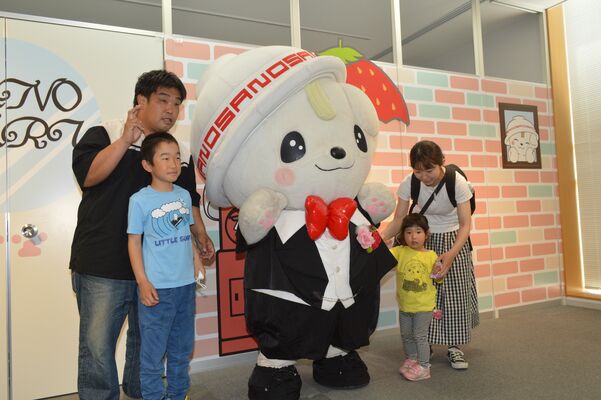 新たな「さのまるの家」の前で写真を撮るさのまると来場者