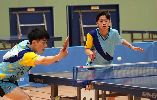 卓球男子ダブルス決勝リーグ　バックハンドを放つ青藍泰斗の赤尾（左）。右は青柳＝県北体育館、橋本裕太撮影