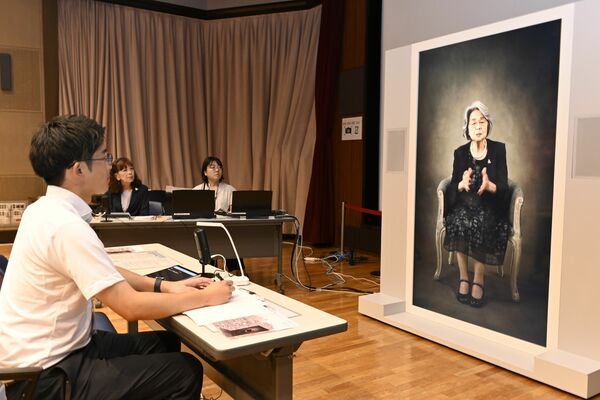 画面上に映し出された等身大の被爆者から体験を聞く本紙記者＝29日午後、広島市中区