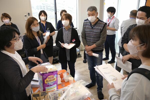 医療的ケア児に最低限必要な約３日分の荷物を見学し、担当者から話を聞く参加者ら