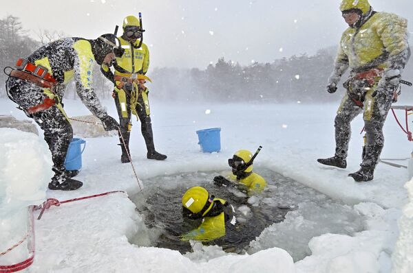 猛吹雪の中、氷結した湯ノ湖で潜水訓練する隊員たち=13日午後4時20分、日光市湯元、永嶌理絵撮影