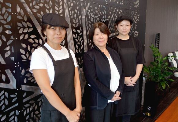自慢の鈑金アートの前に立つ谷内さん（中央）とスタッフたち