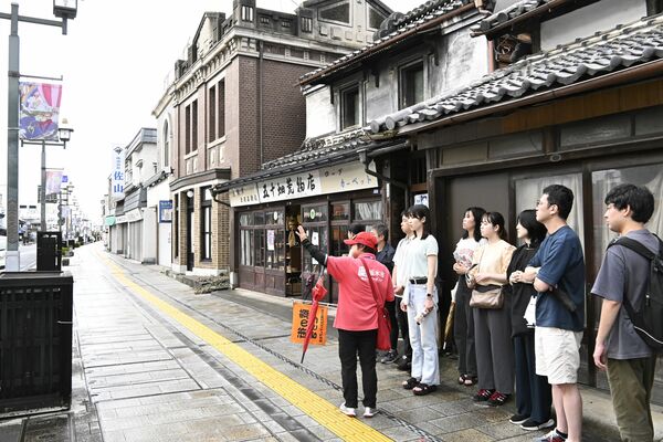 観光ガイドの案内を受けて市内の散策を楽しむ観光客ら