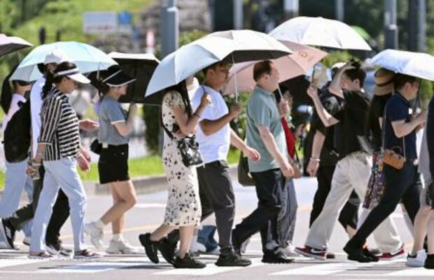 　昨年６月、強い日差しに日傘を差す人たち＝東京都内