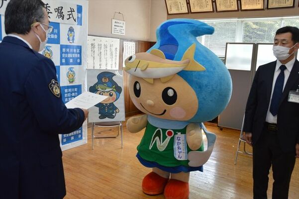 手塚署長（左）から委嘱状を手渡されるなかちゃん（中央）