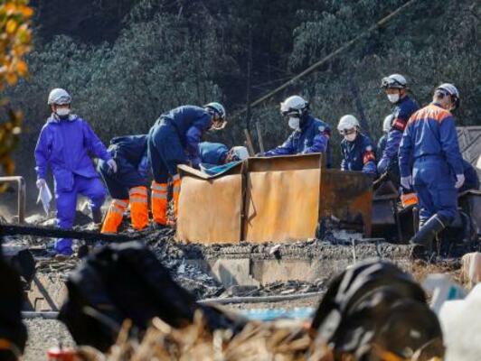 　正琳寺の住居兼本堂などが全焼した現場を調べる警察官ら＝２１日午前１０時６分、山口県下関市