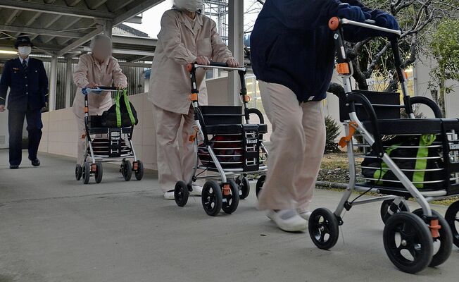 作業終了後、刑務官に見守られ、手押し車に頼って自室に戻る高齢受刑者=2015年2月26日午後(画像は一部加工しています)