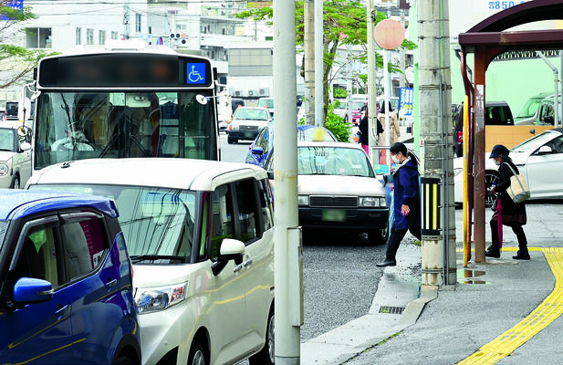 バス停付近にレンタカー３台とタクシー１台が駐停車する中、車道側に止まったバス（左）。バス利用者は、歩道から降りてバスへ乗り込んだ＝３月２０日、那覇市内（画像を一部加工）