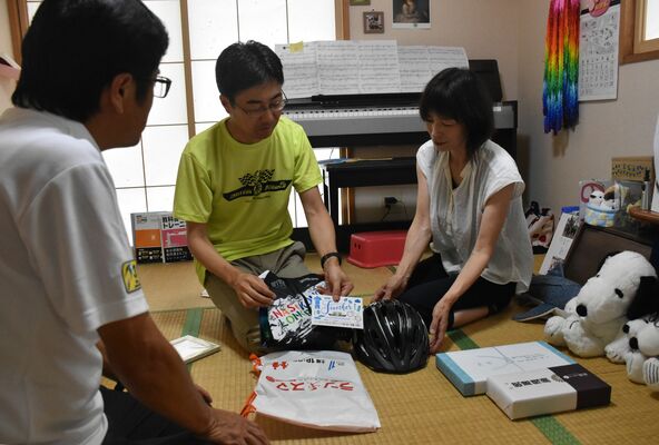 譲さんの名前が書かれた完走証を手にする父慎二さん（中央）と、母道子さん（右）＝18日午後５時55分、那須塩原市東豊浦