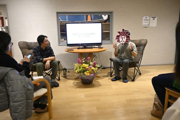 トークイベントを主催する毛利さん（右）。黒子に徹するとの信条からメディアに出る際は会社ロゴのお面を着用している