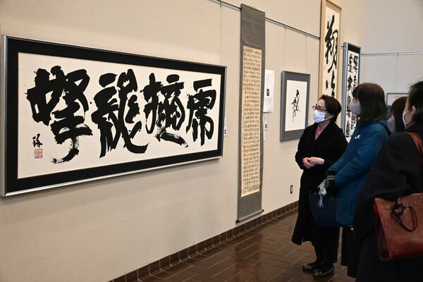 日賀野琢代表の作品（左）を鑑賞する来場者