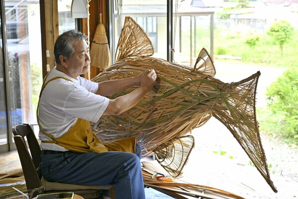 巨大なアユのオブジェの製作を製作する八木澤さん＝29日午後１時、大田原市下石上