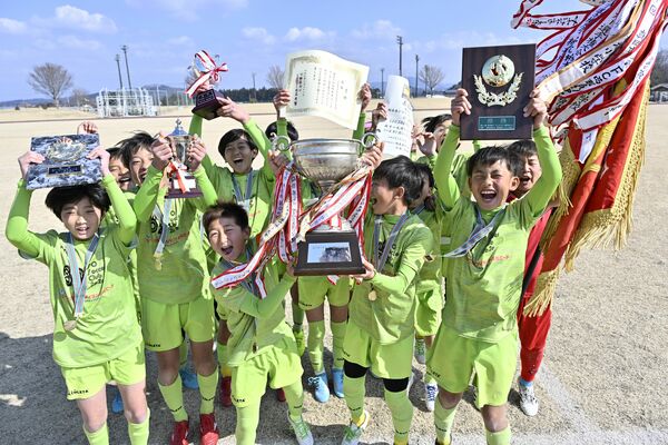 優勝カップなどを掲げ喜びを爆発させるＩＳＯ　ＳＣ（宇河）の選手たち＝真岡ハイトラ運動公園陸上競技場、湯田大士撮影