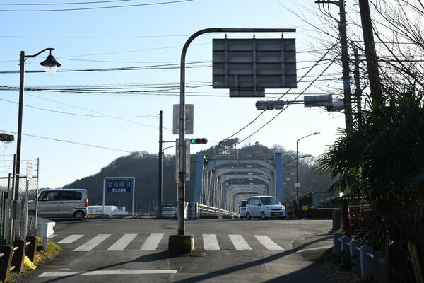 道路の真ん中に設置されている案内標識。奥には渡良瀬橋が見える
