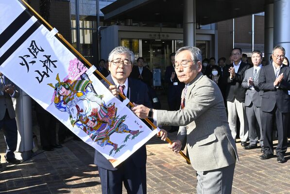 山内副町長（右）から記念品となる武者絵ののぼり旗を受け取る入野町長