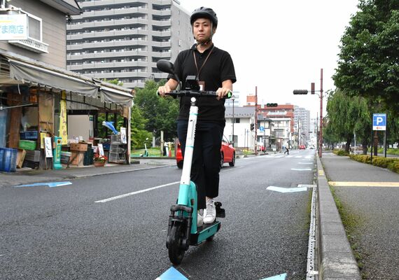 電動キックボードの正しい乗り方示す宇都宮市の担当者。ヘルメットをかぶって車道の左側を走行する＝30日午前、宇都宮市