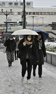 夜間に積もった雪が残る歩道を歩く通勤者＝８日午前７時半、宇都宮市駅前通り１丁目