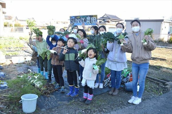 収穫した野菜を手にする子どもたち