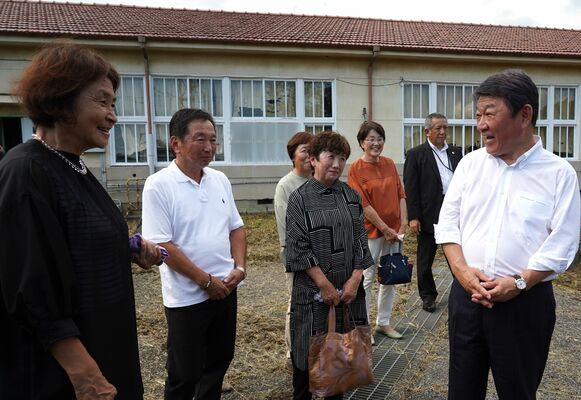 母校の分校跡で同級生らと談笑する茂木氏（右端）＝11日午後、足利市月谷町