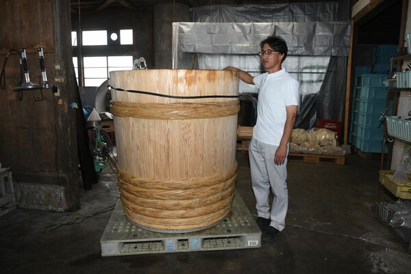 八溝杉で造られた木桶と渡邉社長＝５月、渡邉酒造