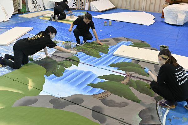舘に滝などの絵を描く岡田さん（中央）ら