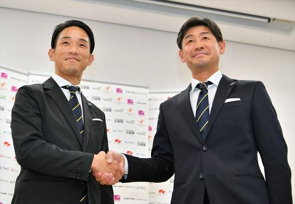 会見で握手する栃木ＳＣの田中新監督（右）と山口強化部長＝26日午後７時35分、宇都宮市宮みらい