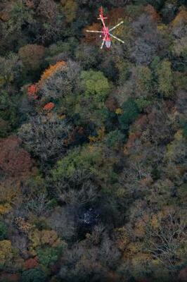 小型機が墜落したとみられる現場(下)で救助活動を行う消防ヘリ=18日午後1時5分、福岡県八女市(共同通信社ヘリから)