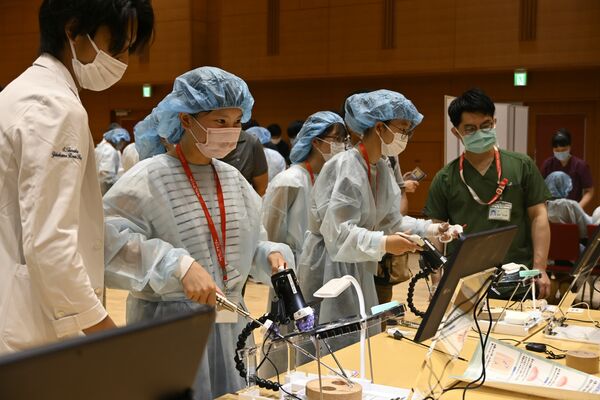 医師の指導を受け内視鏡のトレーニング機器を操作する中学生ら＝17日午後、宇都宮市竹林町