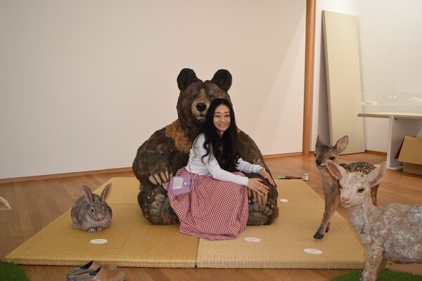 自身の作品に座る彫刻家のはしもとみおさん