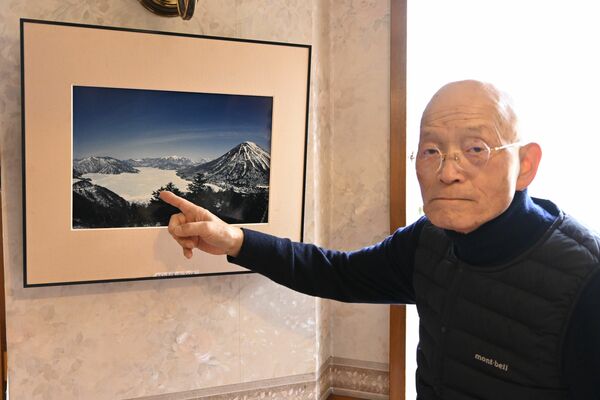 中禅寺湖が雪原へと変わった当時の写真を説明する福田さん
