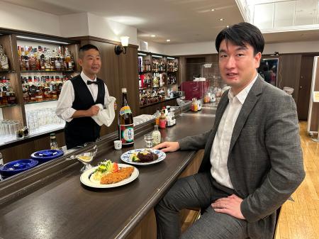 京橋モルチェの定番メニューと共に、月桂冠の日本酒「上撰」を味わう大倉泰治副社長=東京・京橋(提供写真)