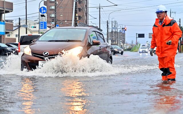冠水した道路で水しぶきを上げて走る乗用車＝６日午後５時15分、宇都宮市今泉新町