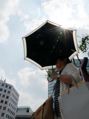 強い日差しの中、福岡市の繁華街で日傘を差して歩く人。九州北部が梅雨明けした=8日午後