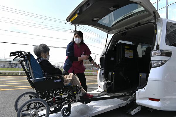 明るく声をかけながら車いすを福祉車両に移す野澤さん＝４月、上三川町上三川
