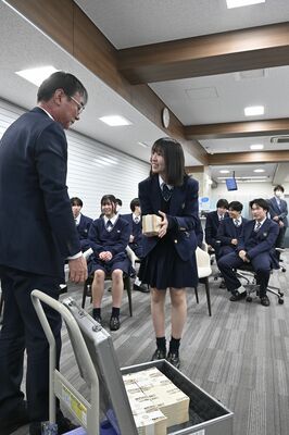 1億円が入ったケースから札束を手にする生徒=宇都宮市