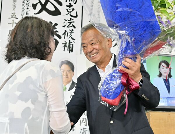 支持者から笑顔で花束を受け取る高橋克法氏（右）＝20日午後10時55分、宇都宮市戸祭町
