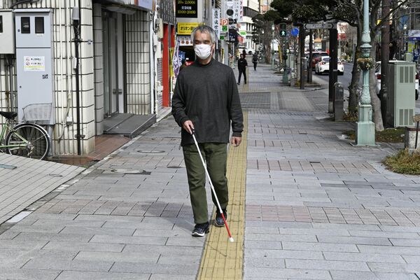 点字ブロックと手に持つ白杖を頼りに歩く渡辺さん＝宇都宮市江野町