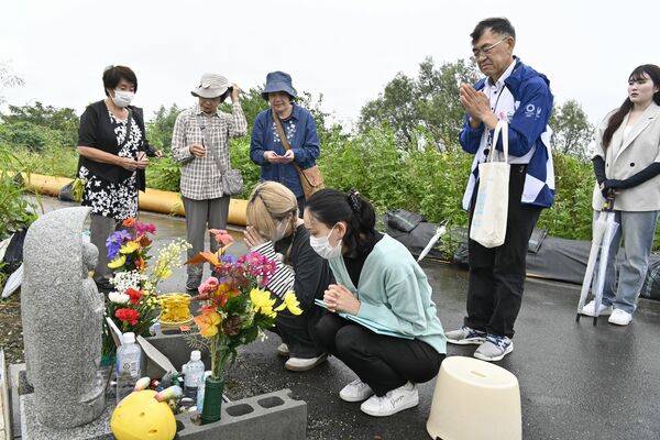 地蔵に手を合わせる学生ら