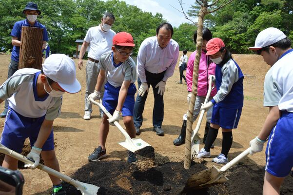 児童と植樹した新井社長（中央）