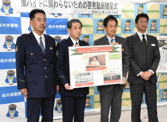 阿久澤教育長（中央右）にパネルを手渡す佐藤生活安全部長（中央左）＝24日午後、県庁南別館